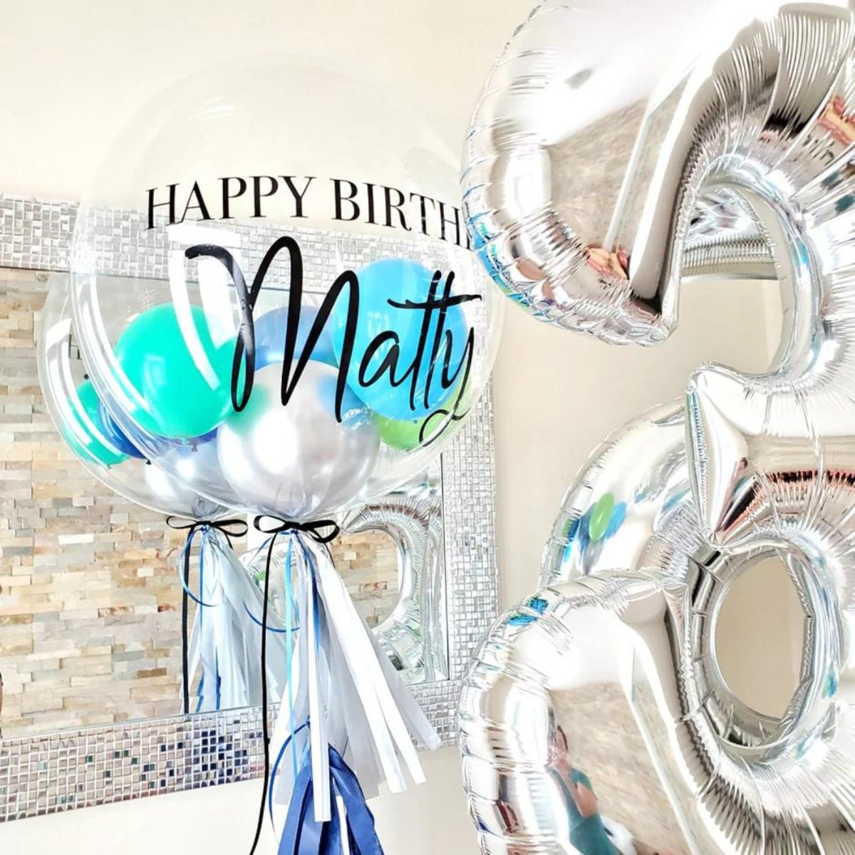 Silver and transparent balloons with "Happy Birthday Matty" text and blue accents.