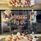 A room with a bride-to-be balloon display, featuring white and gold balloons, creating a festive and celebratory atmosphere.